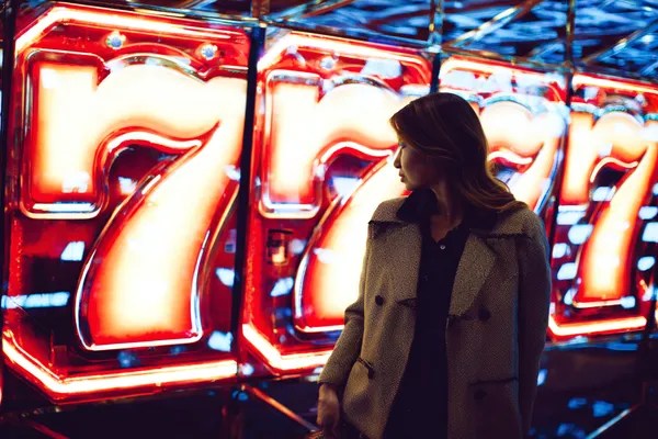 A woman smiling while playing online games on her laptop, surrounded by neon casino elements, showcasing BB444’s diverse game collection.